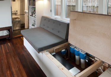 The 8.5′ couch/guest bed opens up to reveal storage, a 40 gal water tank, and water filter. An onboard 3 stage Doulton filter system originally designed for freshwater boaters makes collected rainwater water potable for shower and sinks.