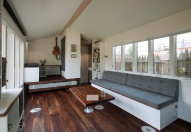 The walnut table may be lowered on a gas-assisted post to become the coffee table.